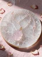 Rose quartz fox charm necklace resting on selenite plate with palo santo smoke